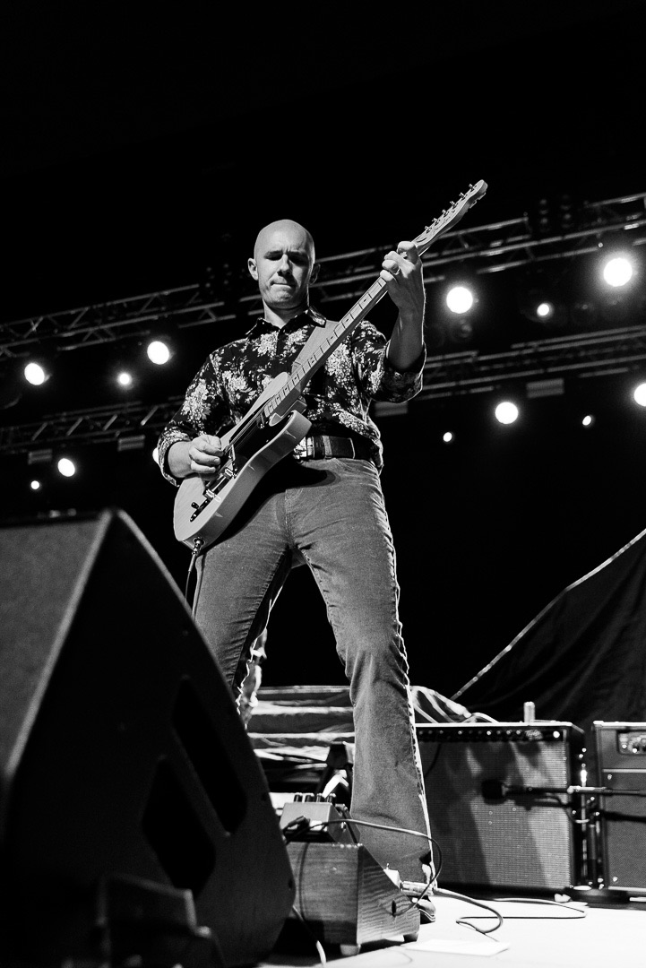 Matt Peace playing lead guitar at the edge of the stage