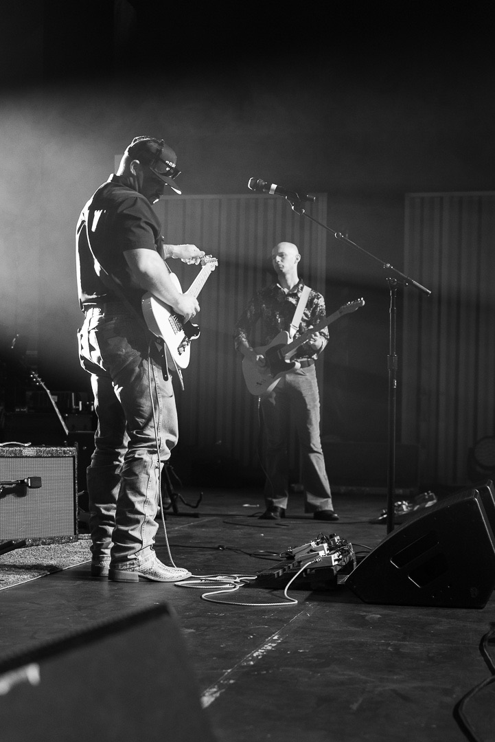 Two guitars facing off under stage light